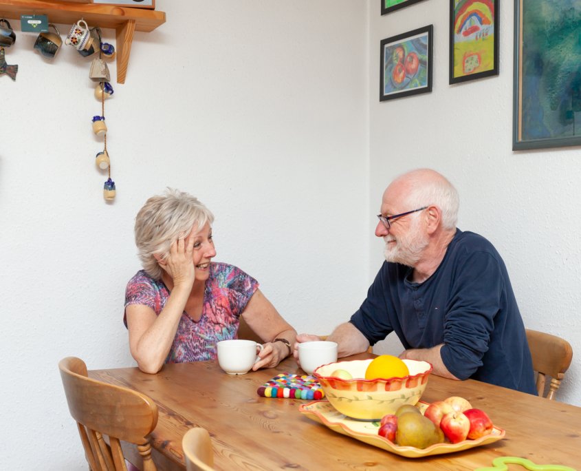 A happy couple sitting in the kitchen enjoying the warmth of their external wall insulation