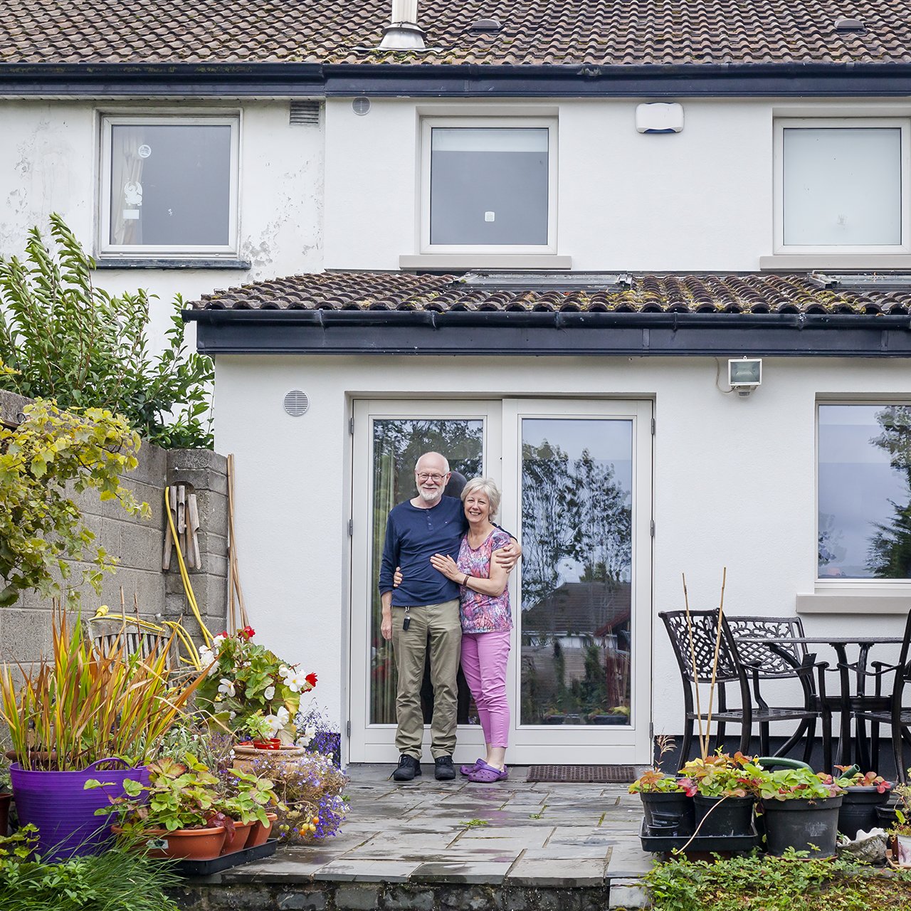 Happy couple standing outside thier house with External Wall Insulation