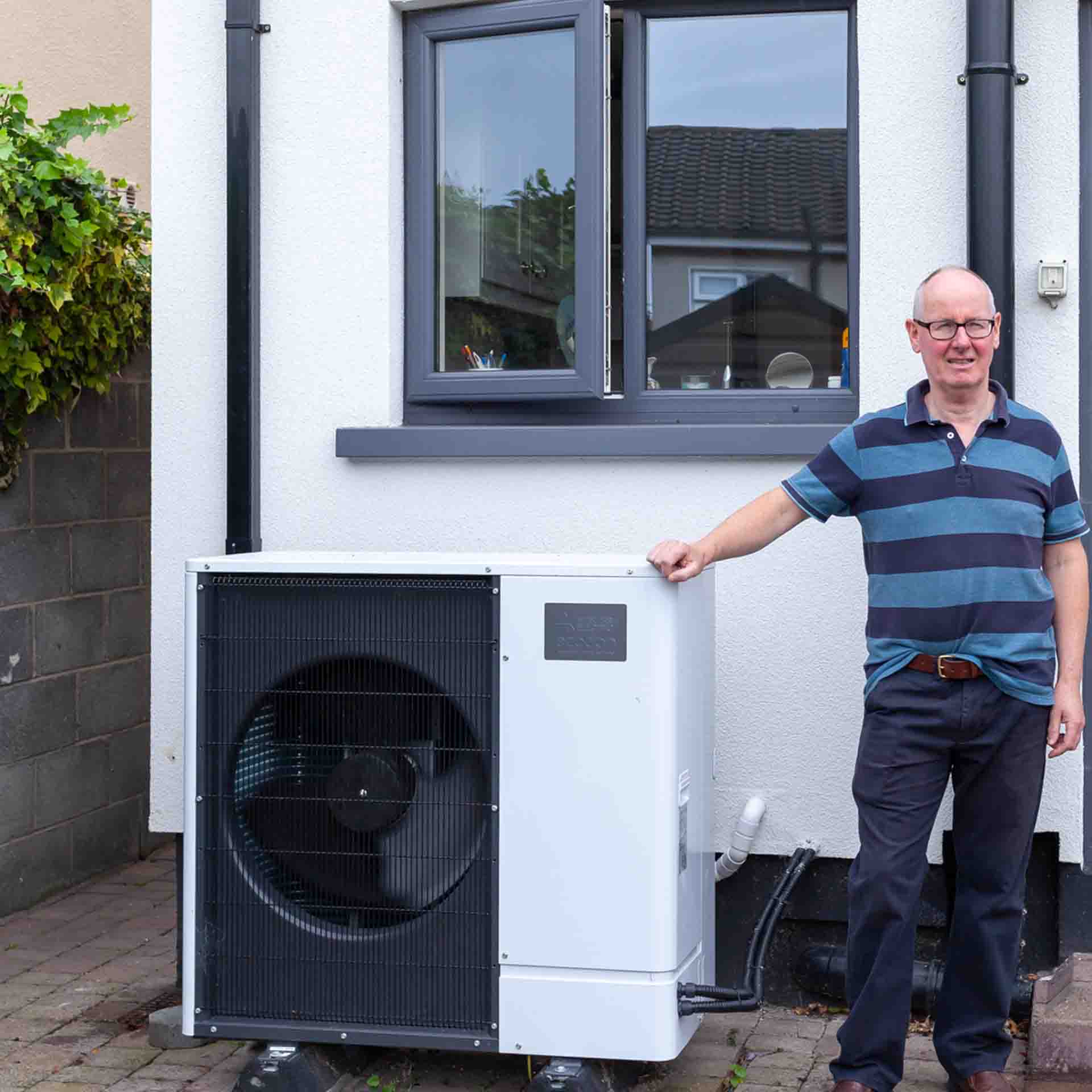 Man standing beside a Heat Pump outside his home